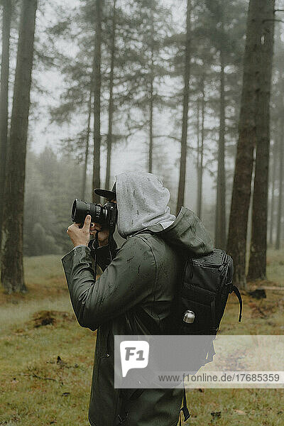Male photographer with SLR camera in rainy woods  Derwent  Derbyshire  England