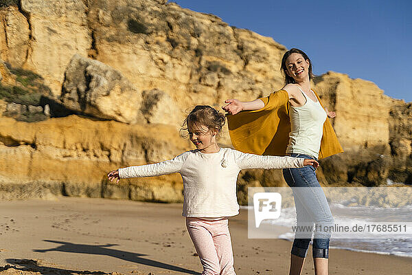 Happy woman with daughter enjoying at beach on sunny day