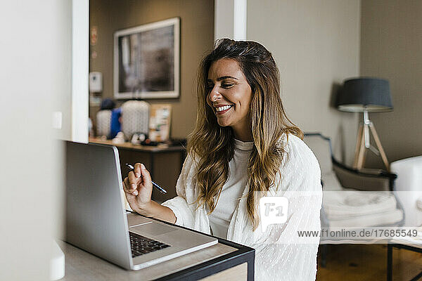 Smiling businesswoman doing video call through laptop at home