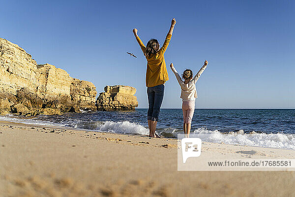 Mother and daughter having fun standing on shore at beach