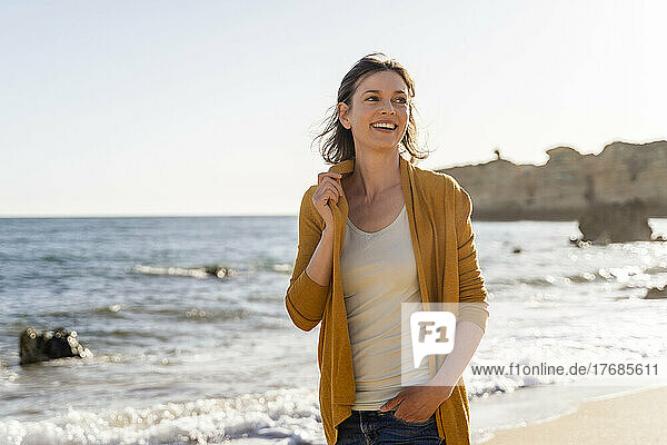 Lächelnde Frau  die an einem sonnigen Tag am Strand steht