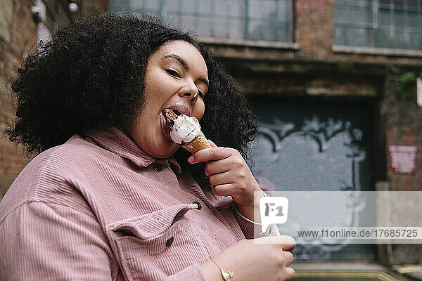 Young woman with curly hair eating ice cream