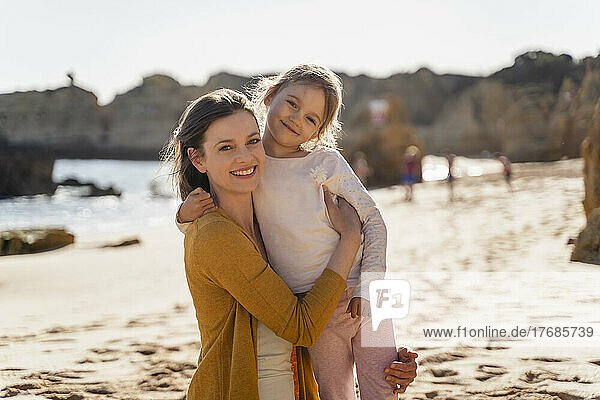 Happy mother with daughter at beach on sunny day