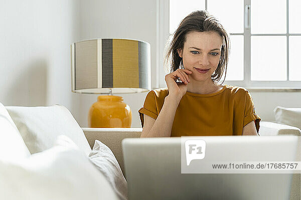Smiling freelancer using laptop in living room working from home