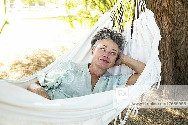 Woman with hand behind head lying in hammock