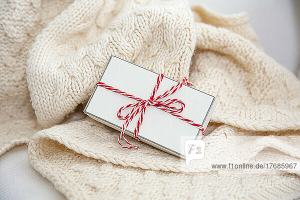 Gift box wrapped with red and white string on woolen blanket