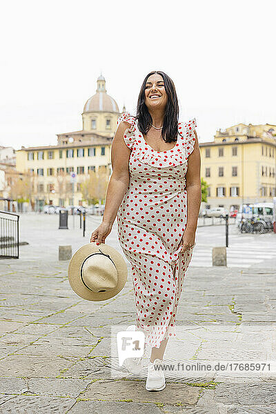 Smiling curvy woman wearing polka dot dress standing in city