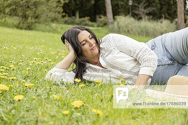 Smiling woman lying on grass at park