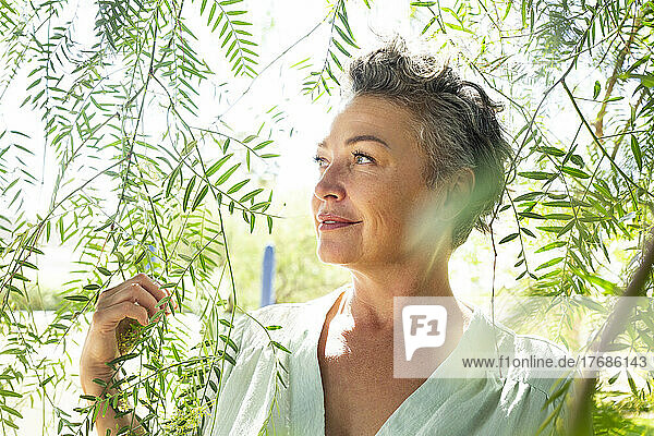Smiling woman standing amidst twigs in garden