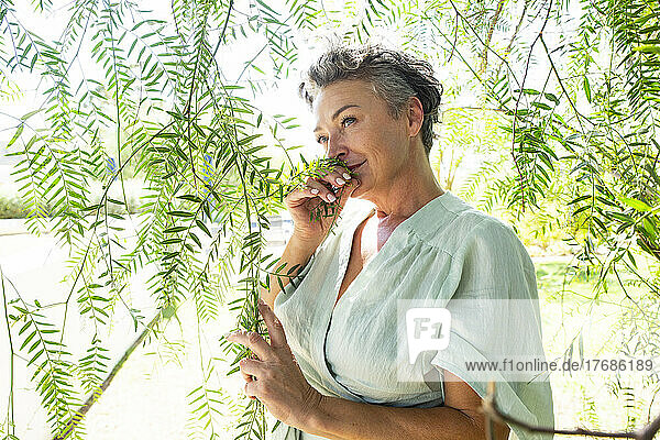 Woman smelling leaves standing in garden