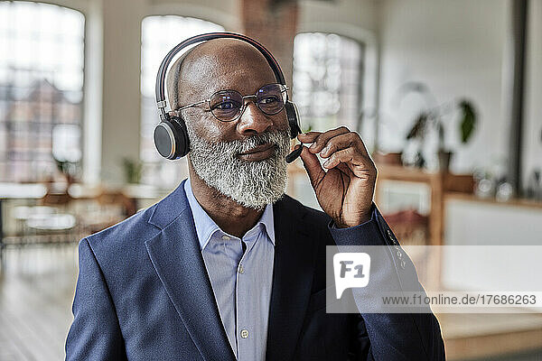 Businessman listening music through headset at home