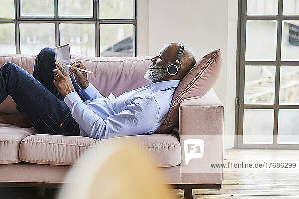 Businessman with headset using digitized pen on tablet PC in living room