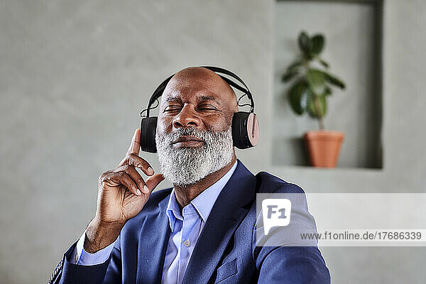 Geschäftsmann mit Glatze genießt zu Hause Musik über kabellose Kopfhörer
