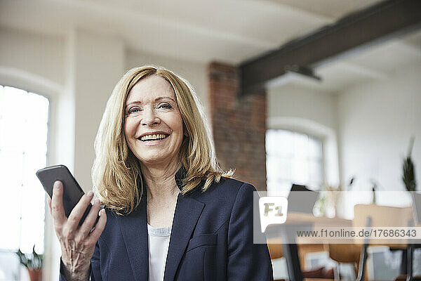 Happy businesswoman with mobile phone at home