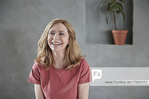 Happy woman in front of gray wall