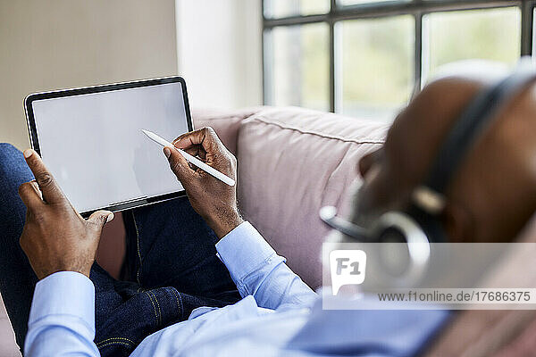 Businessman using digitized pen on tablet PC at home