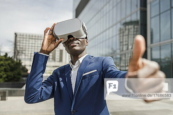 Businessman wearing virtual reality simulator showing thumbs up