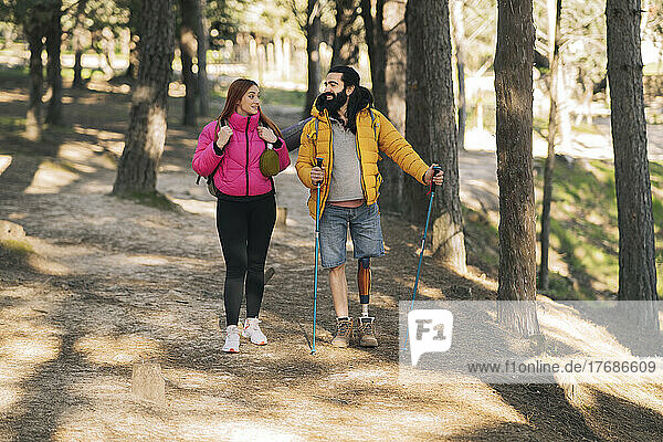 Lächelnder behinderter Mann wandert mit Freundin im Wald