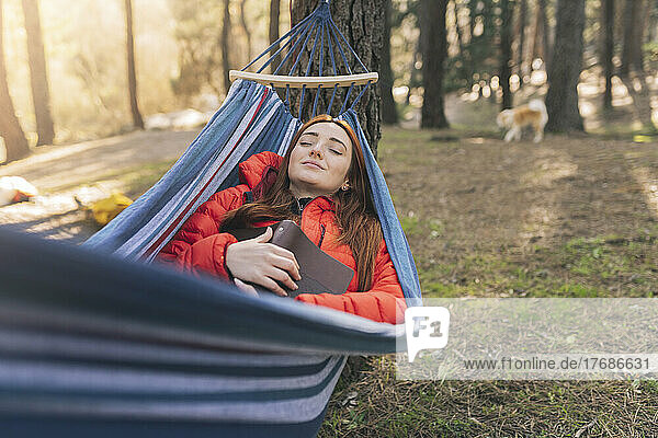Young woman with eyes closed resting in hammock