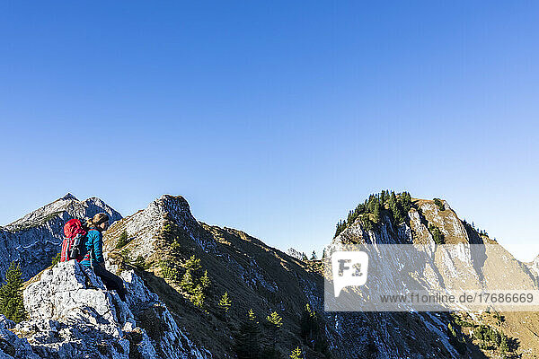 Germany  Bavaria  Female hiker relaxing on mountaintop in Ammergau Alps