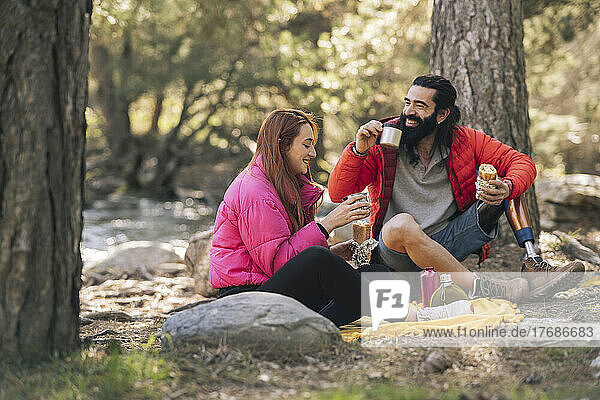 Happy couple with food and drink enjoying in forest