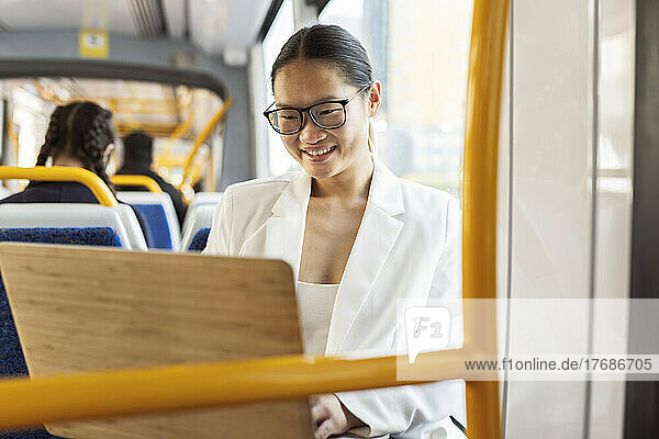 Smiling businesswoman using laptop in tram