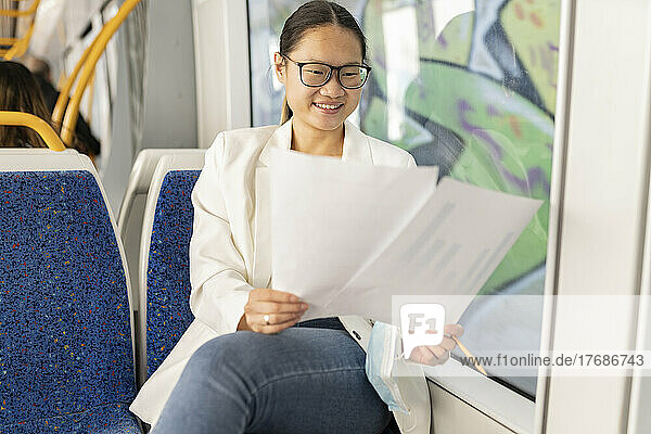 Happy businesswoman analyzing document in tram