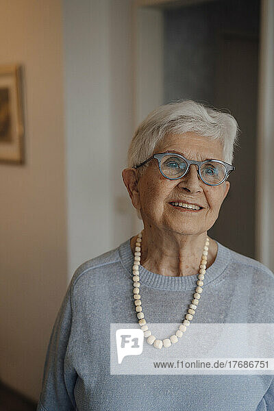 Smiling senior woman wearing eyeglasses standing at home
