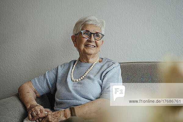 Smiling senior woman sitting on sofa at home