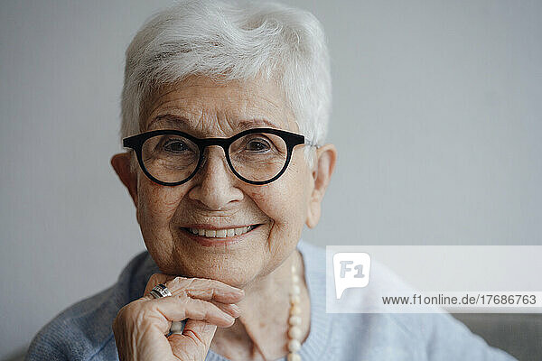 Happy senior woman with hand on chin at home