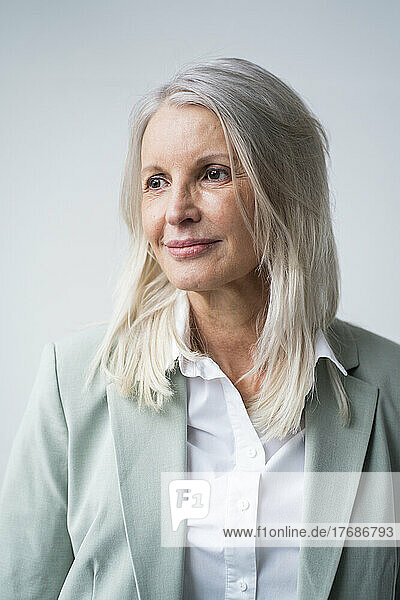 Contemplative senior businesswoman against white background