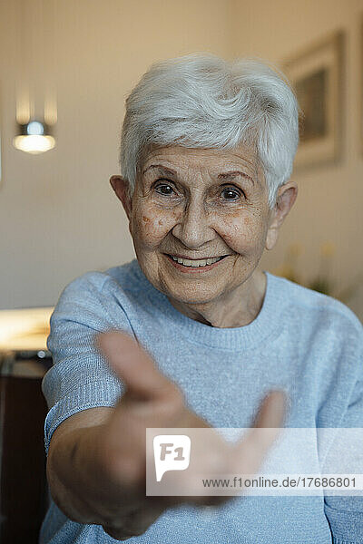 Happy senior woman giving hand at home