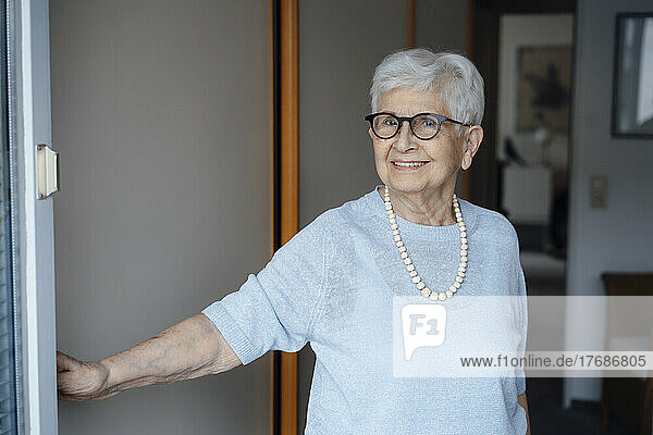 Happy senior woman with white hair standing at doorway