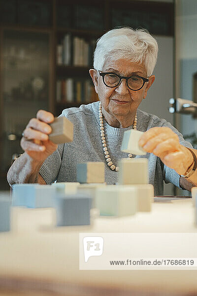 Smiling senior woman playing with toy blocks at home