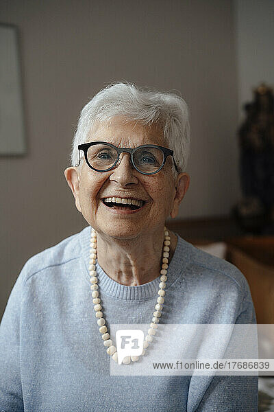 Happy senior woman wearing eyeglasses sitting at home