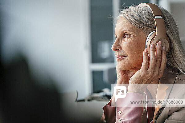 Geschäftsfrau träumt davon  im Büro Musik über Kopfhörer zu hören