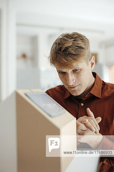 Businessman with hands clasped looking at house model in office
