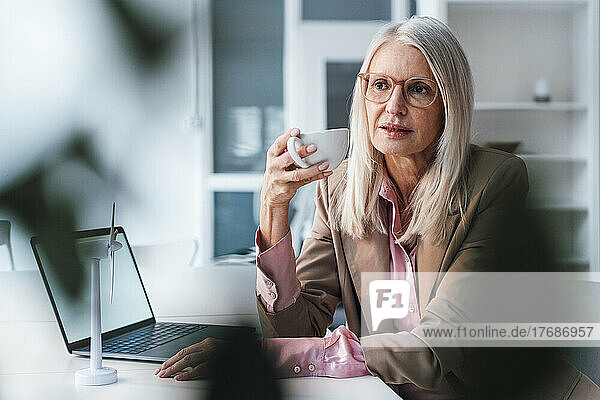 Businesswoman having coffee sitting at desk at office