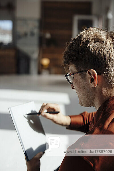 Businessman with digitized pen writing on tablet PC in office