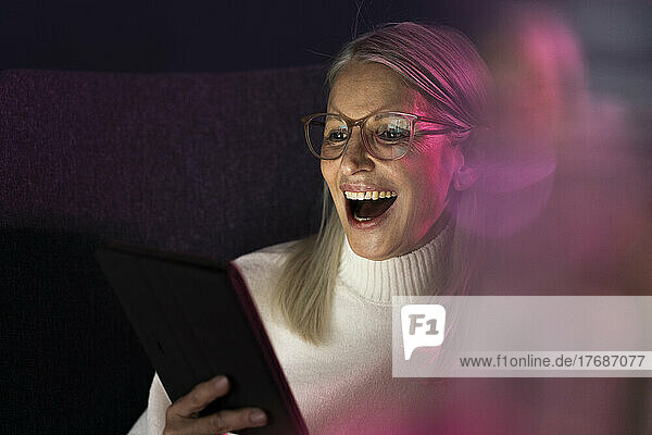 Laughing senior woman looking at tablet PC