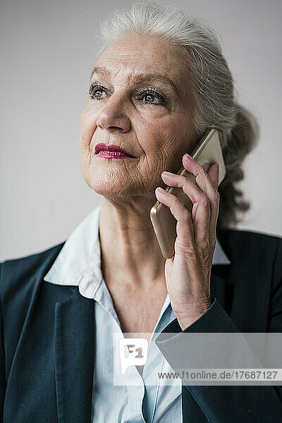 Geschäftsfrau spricht auf Smartphone vor weißem Hintergrund