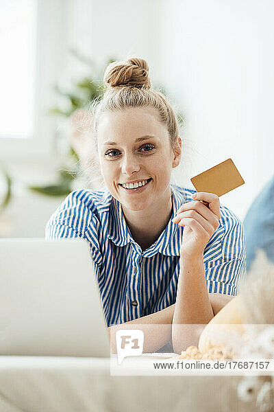 Geschäftsfrau zeigt Kreditkarte im Liegen zu Hause
