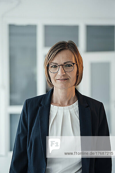 Smiling businesswoman wearing eyeglasses standing at office