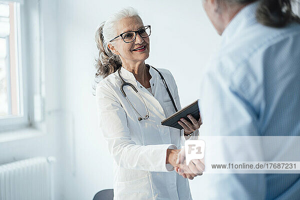 Smiling senior doctor shaking hands with patient