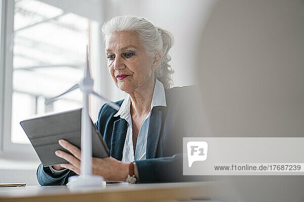 Senior businesswoman using tablet PC sitting at desk in office