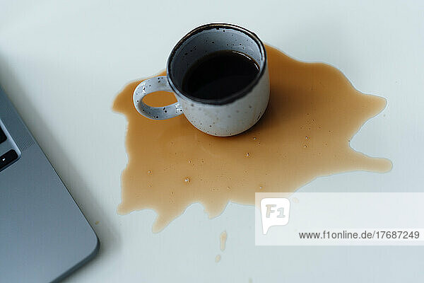 Spilled coffee by laptop on desk