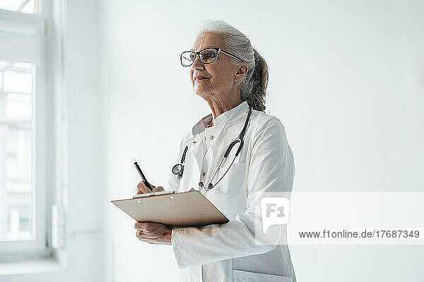 Doctor wearing eyeglasses standing with clipboard