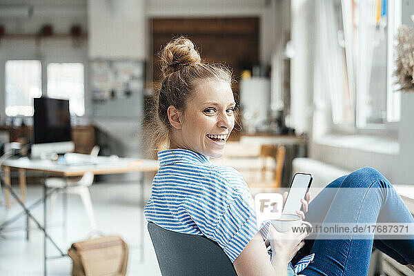 Cheerful businesswoman looking over shoulder sitting at home