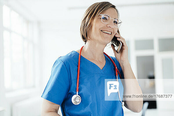 Smiling female doctor talking on smart phone in medical clinic