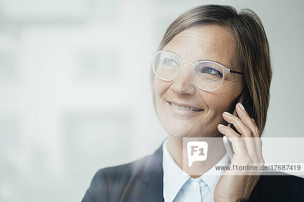 Happy businesswoman with brown hair talking on mobile phone